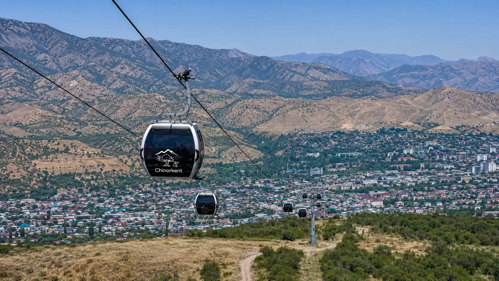 A Chinorkent gondola cabin crossing the foothills above the town.
